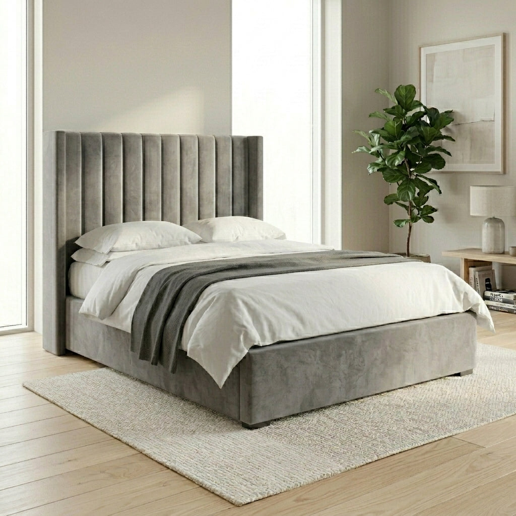 A gray upholstered Wing bed with a tall channel-tufted headboard and matching footboard, shown in a bright bedroom setting with white bedding 